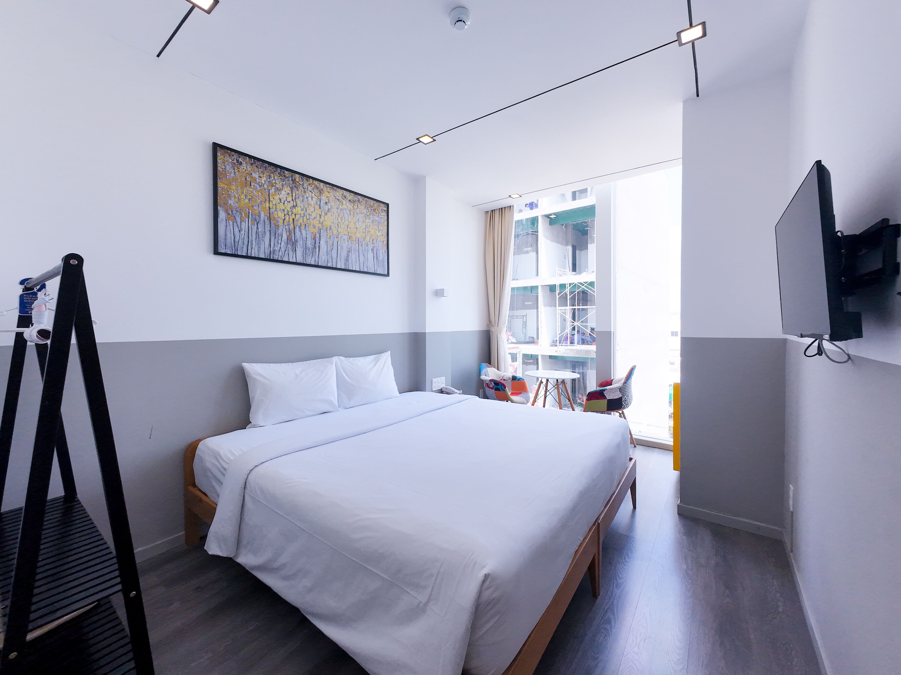 Habitación de hotel moderna con una cama grande, un escritorio, una silla, un televisor y una ventana con vistas al exterior.