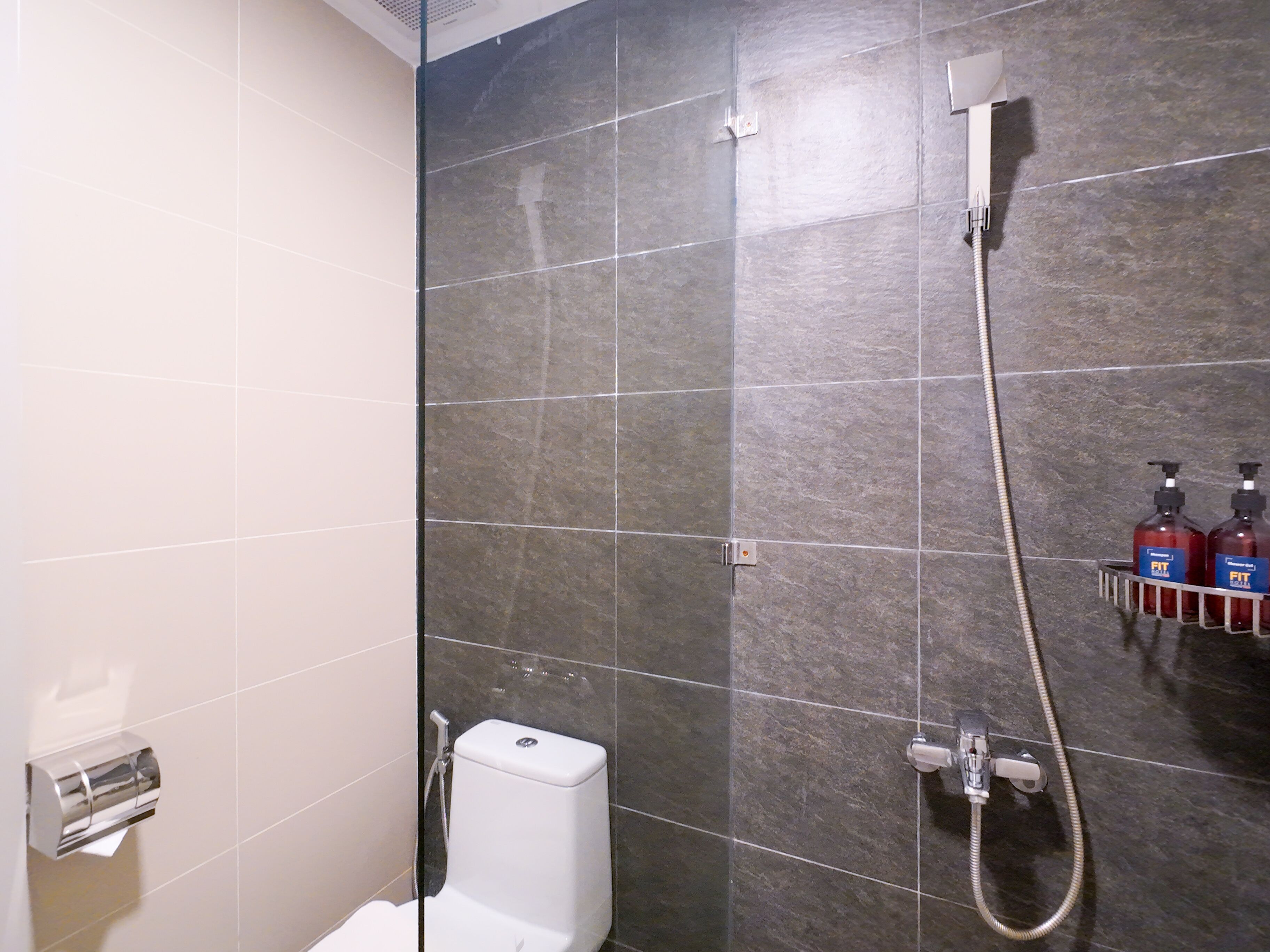 A shower area with a glass door, a white toilet, and a hand dryer.
