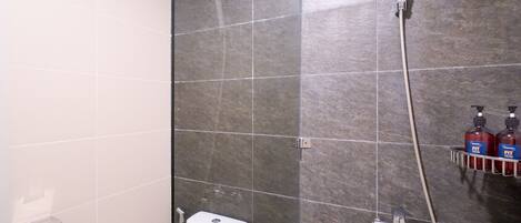 A shower area with a glass door, a white toilet, and a hand dryer.