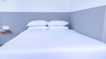 Ein Einzelbett mit weißer Bettwäsche in einem Zimmer mit hellgrauen Wänden.