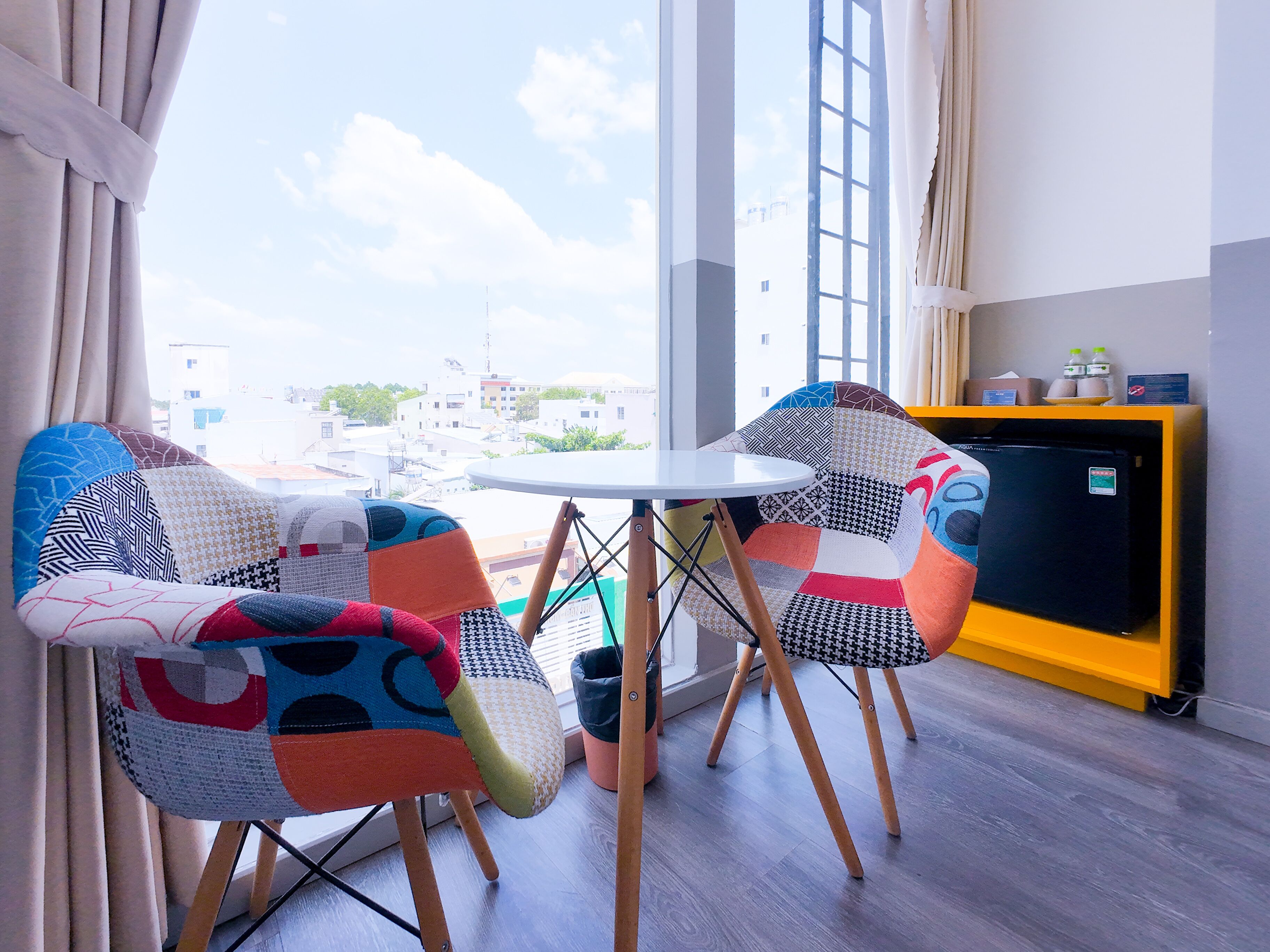Une pièce avec deux chaises colorées, une petite table et un meuble jaune.