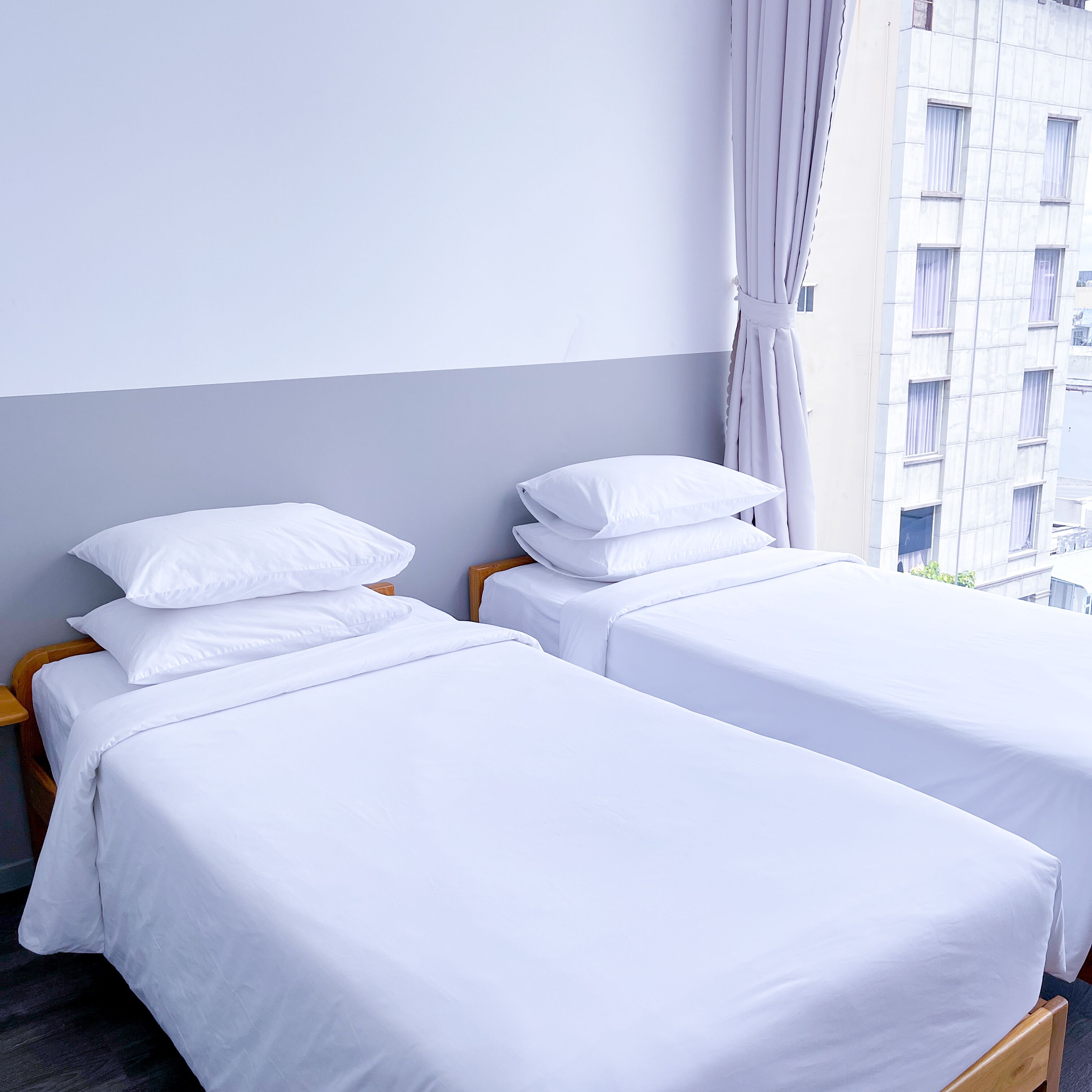 Twee eenpersoonsbedden met witte lakens in een hotelkamer.