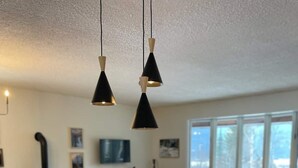 Una cocina con encimera de madera, armarios blancos y dos lámparas colgantes.