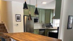 Una cocina moderna con una isla de madera, taburetes de bar e iluminación colgante.