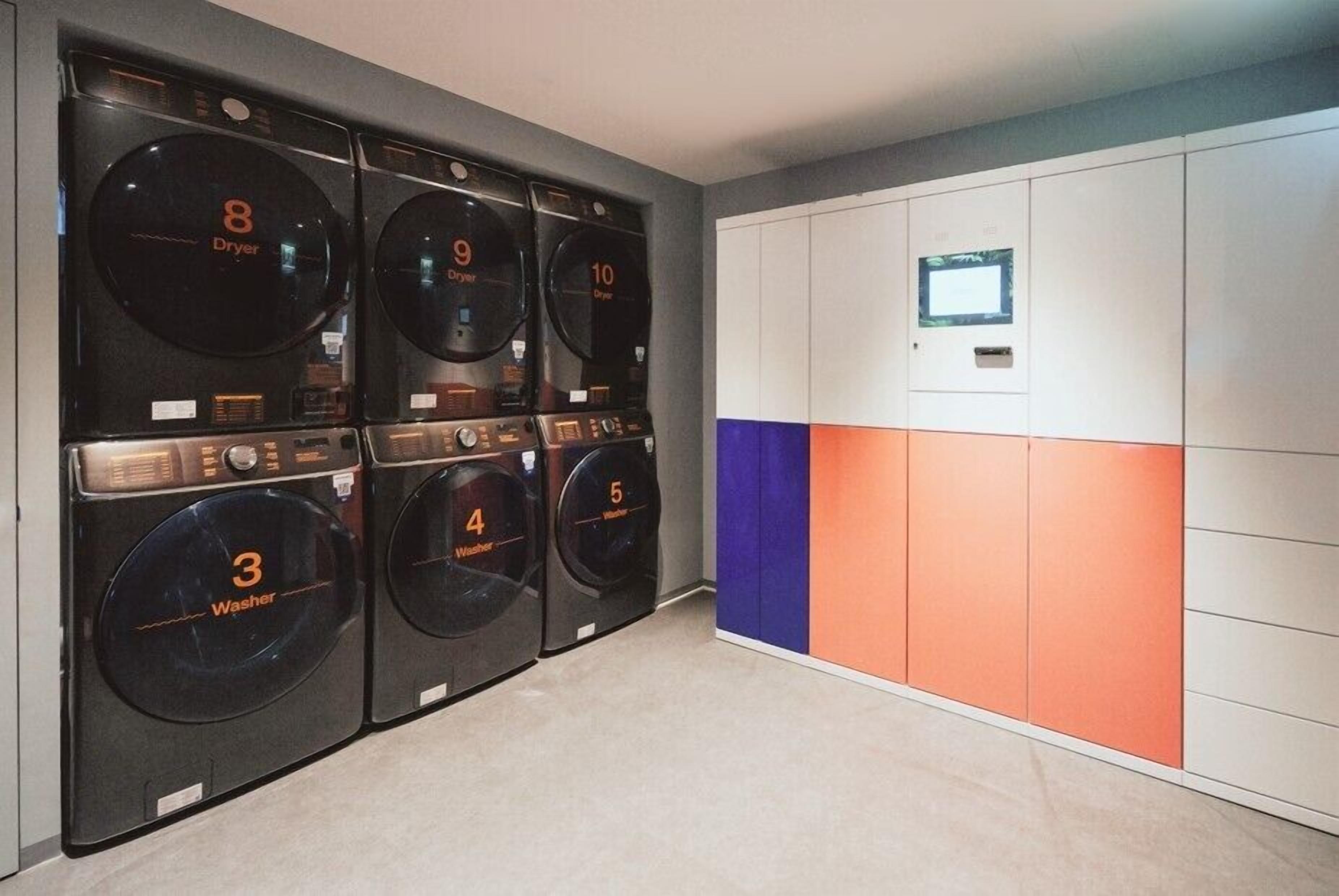 Een wasserette met zes wasmachines en drogers, genummerd van 3 tot 10, en een bedieningspaneel met een digitaal scherm.