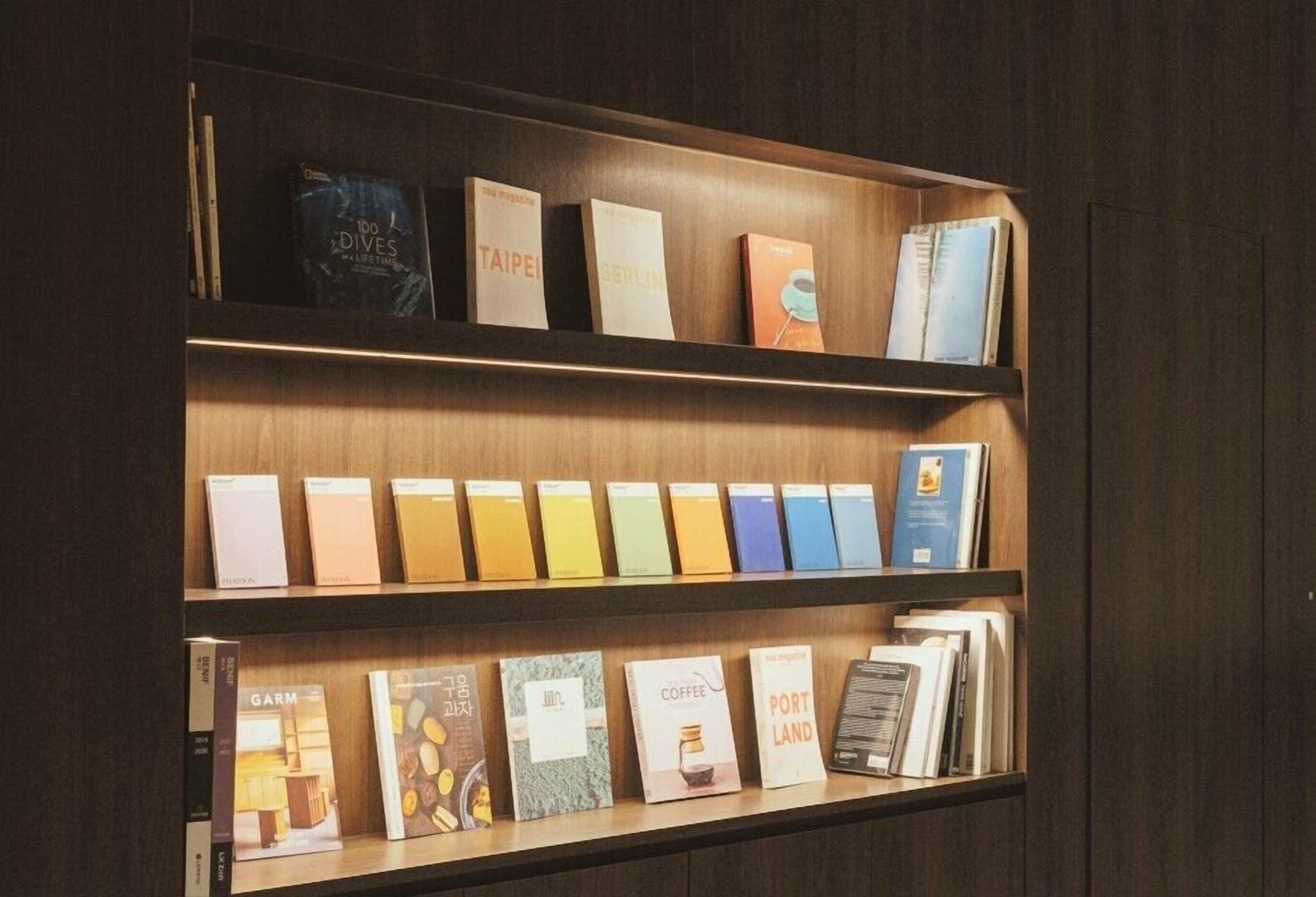 A bookshelf with books and magazines, some with visible titles and others with covers.