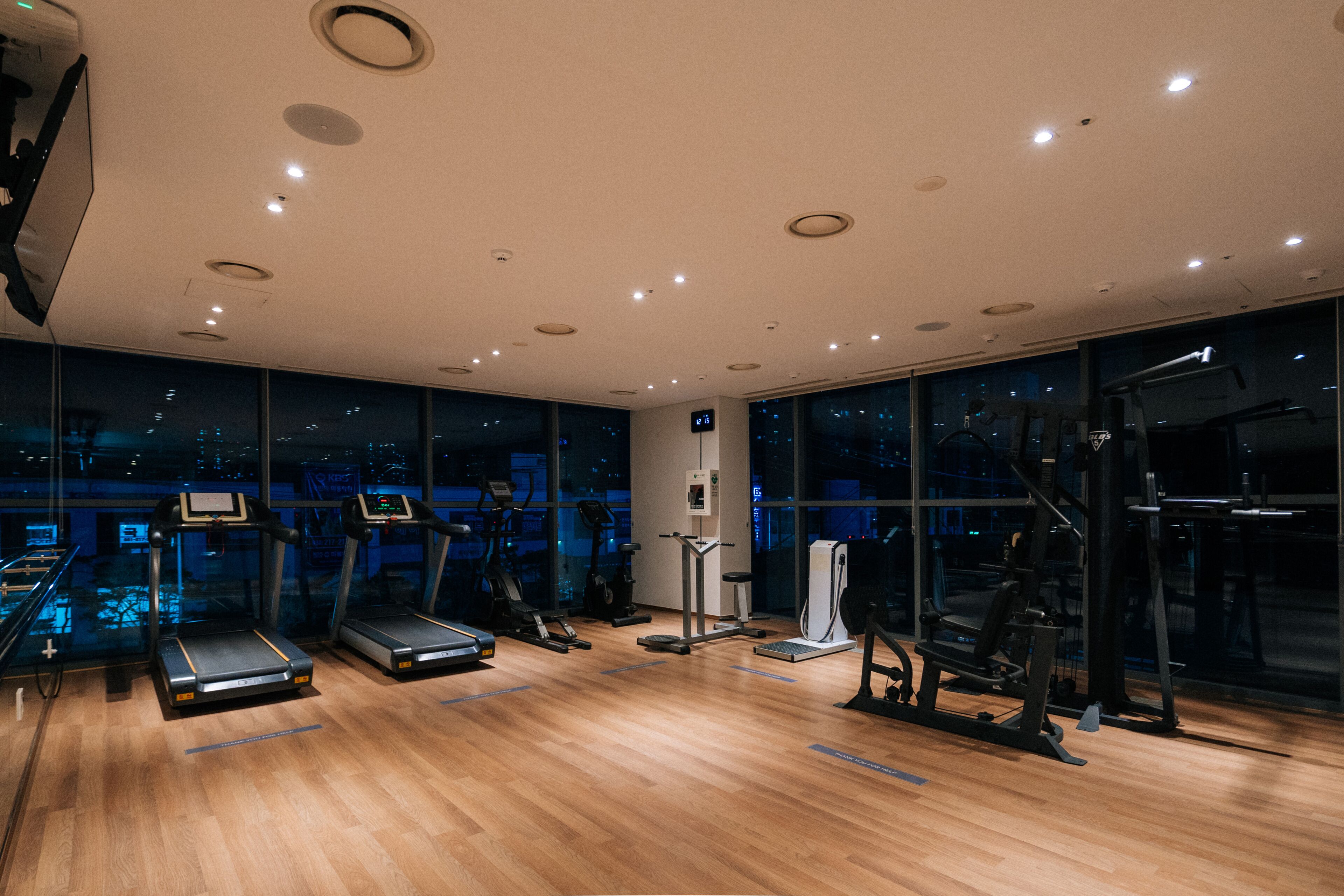 A modern gym with treadmills, elliptical machines, and weight equipment.
