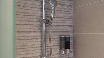 A shower with a handheld showerhead and a wall-mounted control panel.