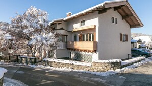 A two-story house with a balcony, stone foundation, and snow-covered surroundings. - Spacious holiday home in the centre (Hopfgarten im Brixental)