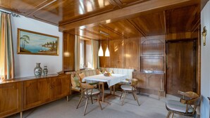 A dining area with a wooden table and chairs, a bench, and a painting on the wall. - Spacious holiday home in the centre (Hopfgarten im Brixental)