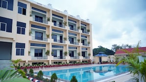 Ein mehrstöckiges Hotel mit Pool, Balkonen mit Geländern und Blumentöpfen.