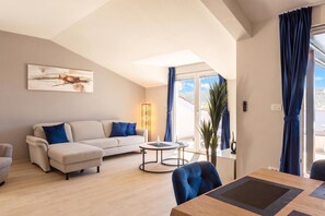 A modern living room with a sofa, a coffee table, and a dining table. - Family Resort Santa Maria II Penthouse (Novalja)
