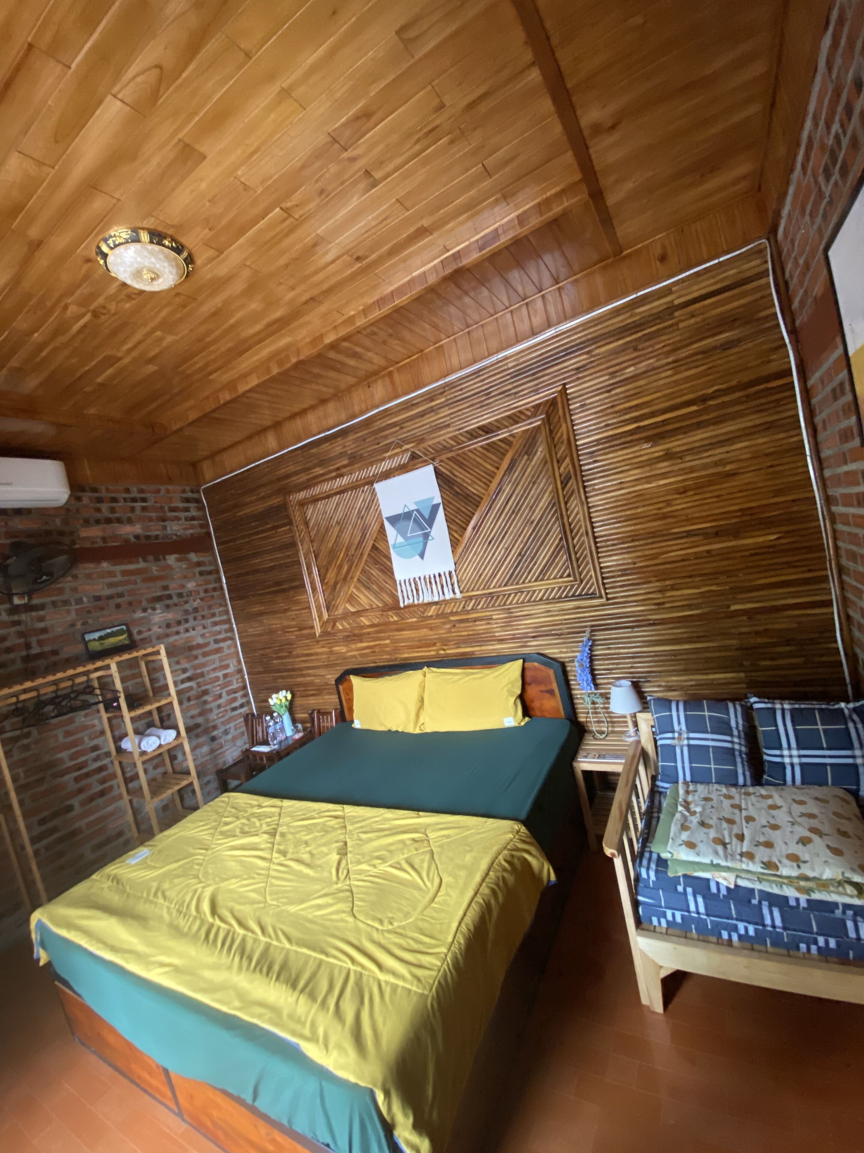 Ein Zimmer mit einem Bett, einem kleinen Tisch, einem Stuhl und einer Holzbalkendecke.