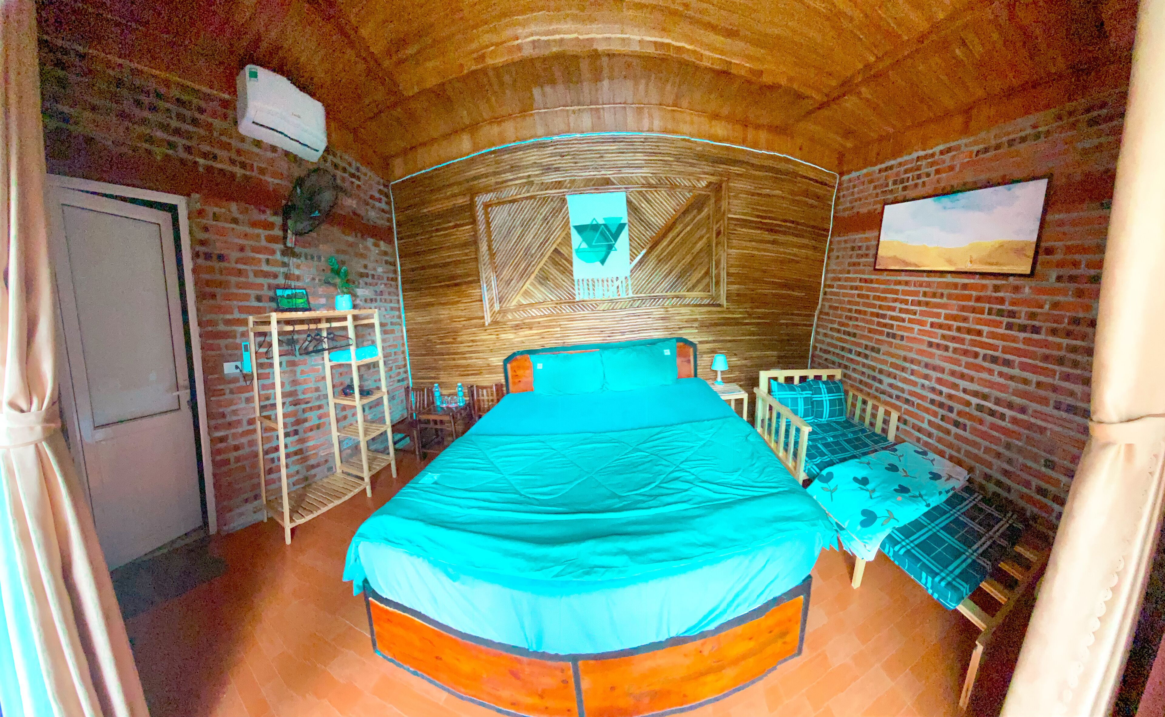 A room with a bed, a small table, a chair, a shelf, and a door.