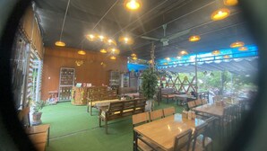 Un restaurant intérieur avec des meubles en bois, des luminaires suspendus et une moquette verte.