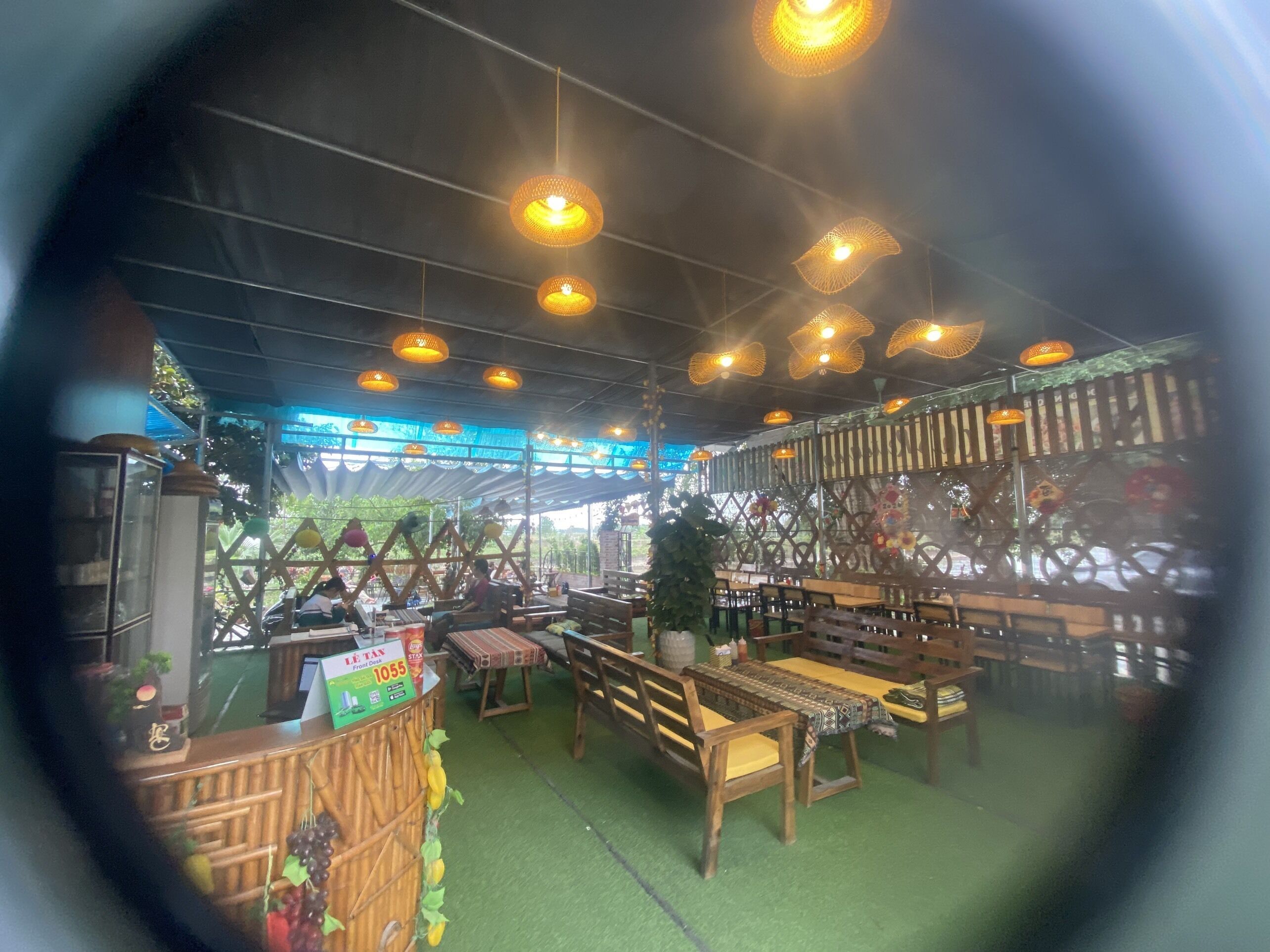 A restaurant with wooden furniture, hanging lights, and a green floor.