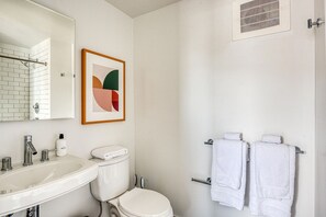 Bathroom features a sink, toilet, and shower area with a glass door.