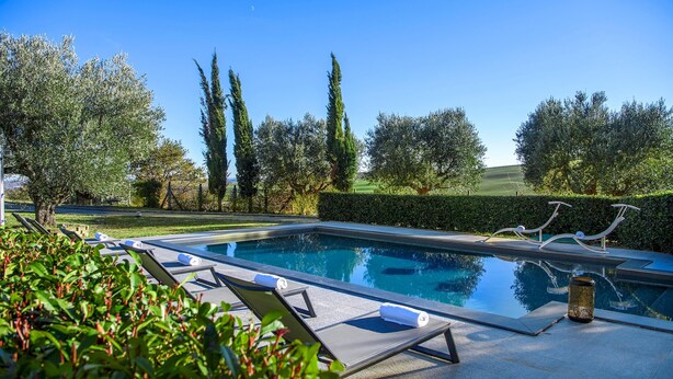 A swimming pool with lounge chairs and a trash can, surrounded by greenery and trees. - Villa Delle Ginestre 9 2 Emma Villas (Cingoli)