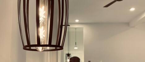Une chambre à coucher moderne avec un lit, un luminaire suspendu et un ventilateur de plafond.