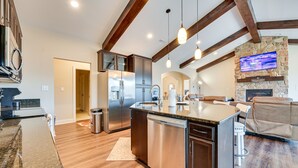 A modern kitchen with stainless steel appliances, a large island, and wooden beams. - 23-Acre Retreat | Wineries, Hiking & Fireplace (Roaring River)