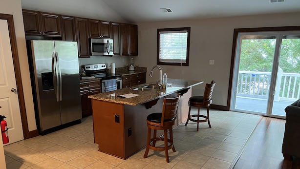 A kitchen with a central island, stainless steel appliances, and a sliding glass door leading to a balcony. - Luxury Beach Side Home Ii 2 Bedroom Home by RedAwning (Norfolk)
