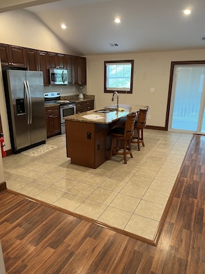 A modern kitchen with a central island, stainless steel appliances, and a large window providing natural light. - Luxury Beach Side Home Ii 2 Bedroom Home by RedAwning (Norfolk)