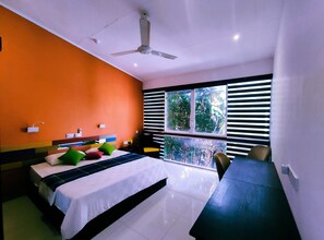 A modern hotel room with a bed, a desk, a chair, and a view of greenery through the window. - The Yacht Near CMB-Bandaranaike Intl. (Seeduwa - Katunayake)