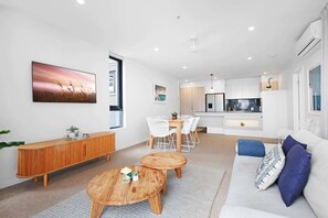 Uma sala de estar moderna com sofá, mesa de centro e área de jantar com cadeiras.