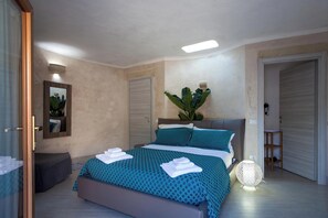 A bedroom with a bed, a bench, a bedside table, a lamp, and a mirror. - Tenuta Bouganville With Garden And Pool (Carpignano Salentino)