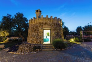 A stone structure with a doorway leading to a room with a bed and a plant. - Tenuta Bouganville With Garden And Pool (Carpignano Salentino)