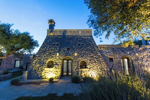 A stone building with a steeply pitched roof, arched doorways, and a chimney. - Tenuta Bouganville With Garden And Pool (Carpignano Salentino)