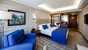 A hotel room with a large bed, two blue armchairs, a painting on the wall, and a patterned carpet. -  Anemon Bursa Hotel (Bursa)