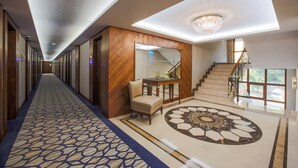 A hotel hallway with a patterned carpet, a chandelier, a staircase, and a view of the outdoors. -  Anemon Bursa Hotel (Bursa)