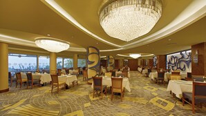 A spacious dining area with multiple tables and chairs, large chandeliers, and a patterned carpet. -  Anemon Bursa Hotel (Bursa)