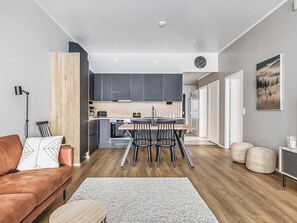 A modern living room with a sofa, a coffee table, and a dining area with chairs and a table. - Villa aava by Interhome (Nilsiä)