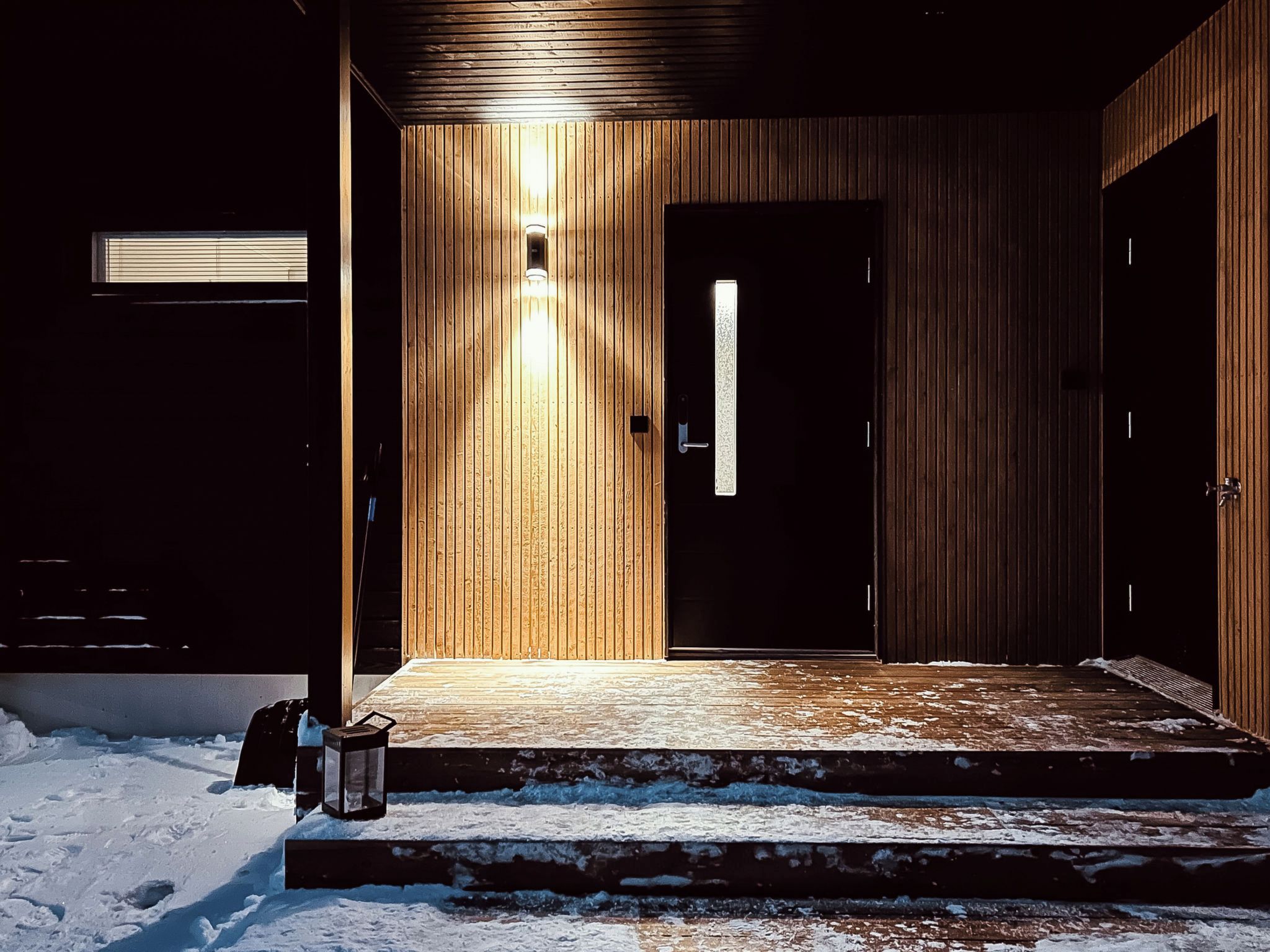 A wooden exterior with a door and a light fixture.