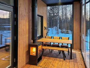 A wooden deck with a wood-burning stove, a table, and benches. - Villa aava by Interhome (Nilsiä)