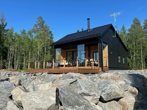 A cabin with a wooden deck, large windows, and a chimney. - Villa aava by Interhome (Nilsiä)