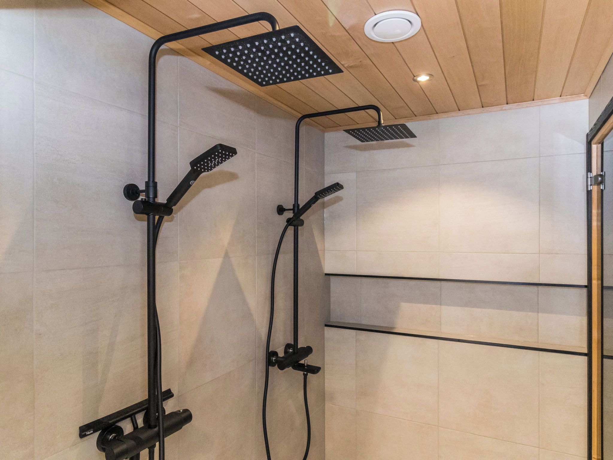 Un baño moderno con zona de ducha que incluye un cabezal de ducha cuadrado y otro manual.