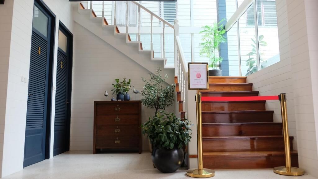 Una escalera con una barrera roja de cuerda, un escritorio de madera con una planta en maceta y un certificado enmarcado en la pared.