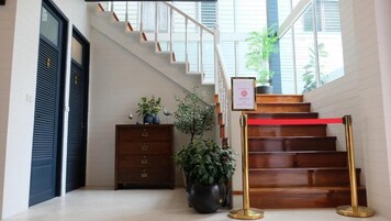 Una escalera con una barrera roja de cuerda, un escritorio de madera con una planta en maceta y un certificado enmarcado en la pared.