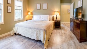 Een slaapkamer met een groot bed, twee nachtkastjes met lampen, een dressoir en een televisie.