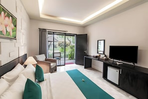 A hotel room with a bed, a desk, a television, and a sliding glass door leading to a balcony. - Belvilla Y Resort Near Central Ubud (Ubud)