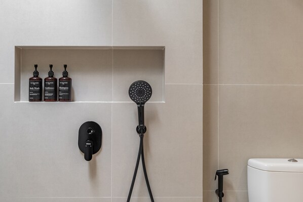 Een badkamer met douche, toilet en een plank met toiletartikelen.