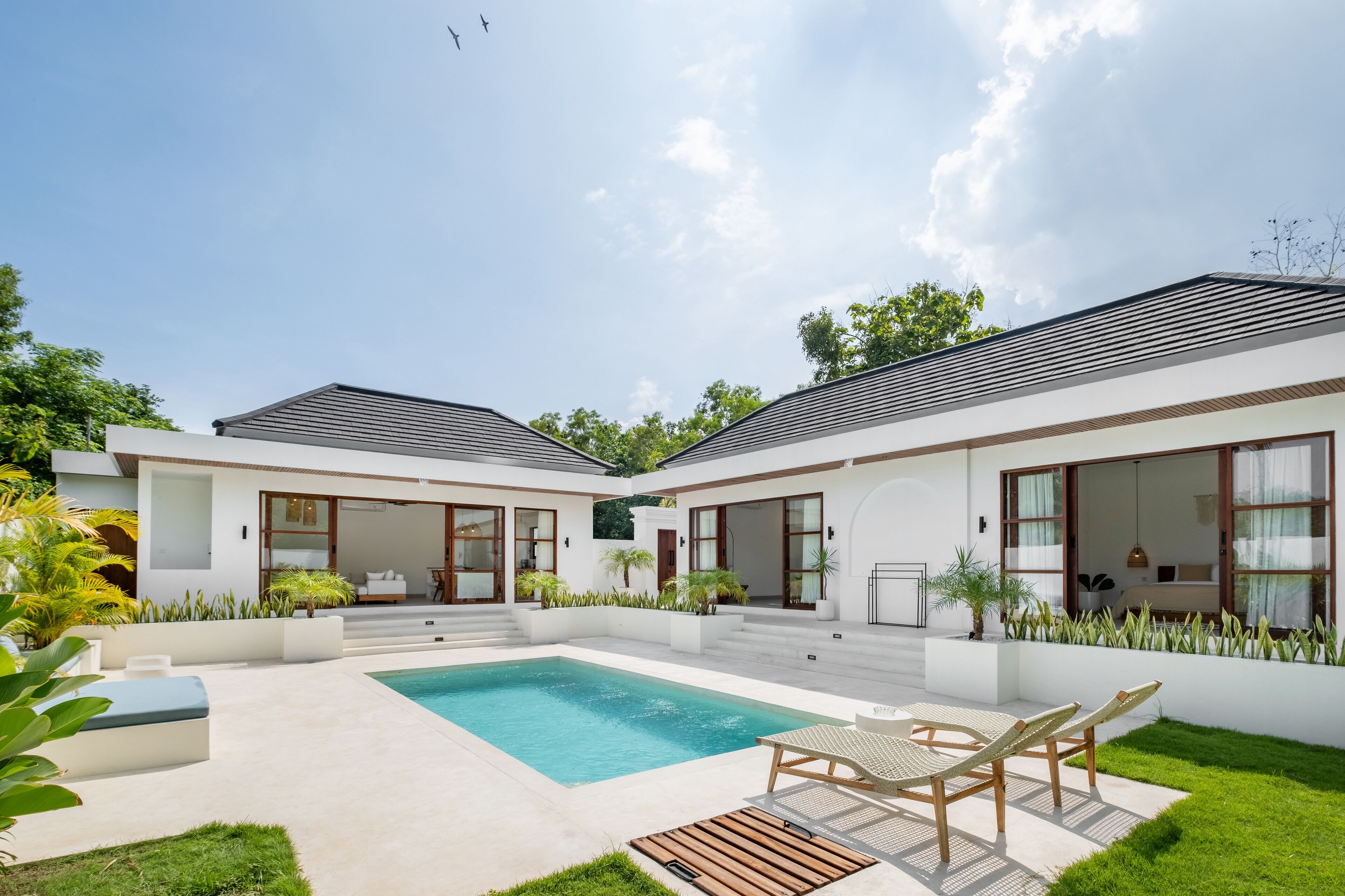 A modern house with a swimming pool, two balconies, and a well-maintained garden.