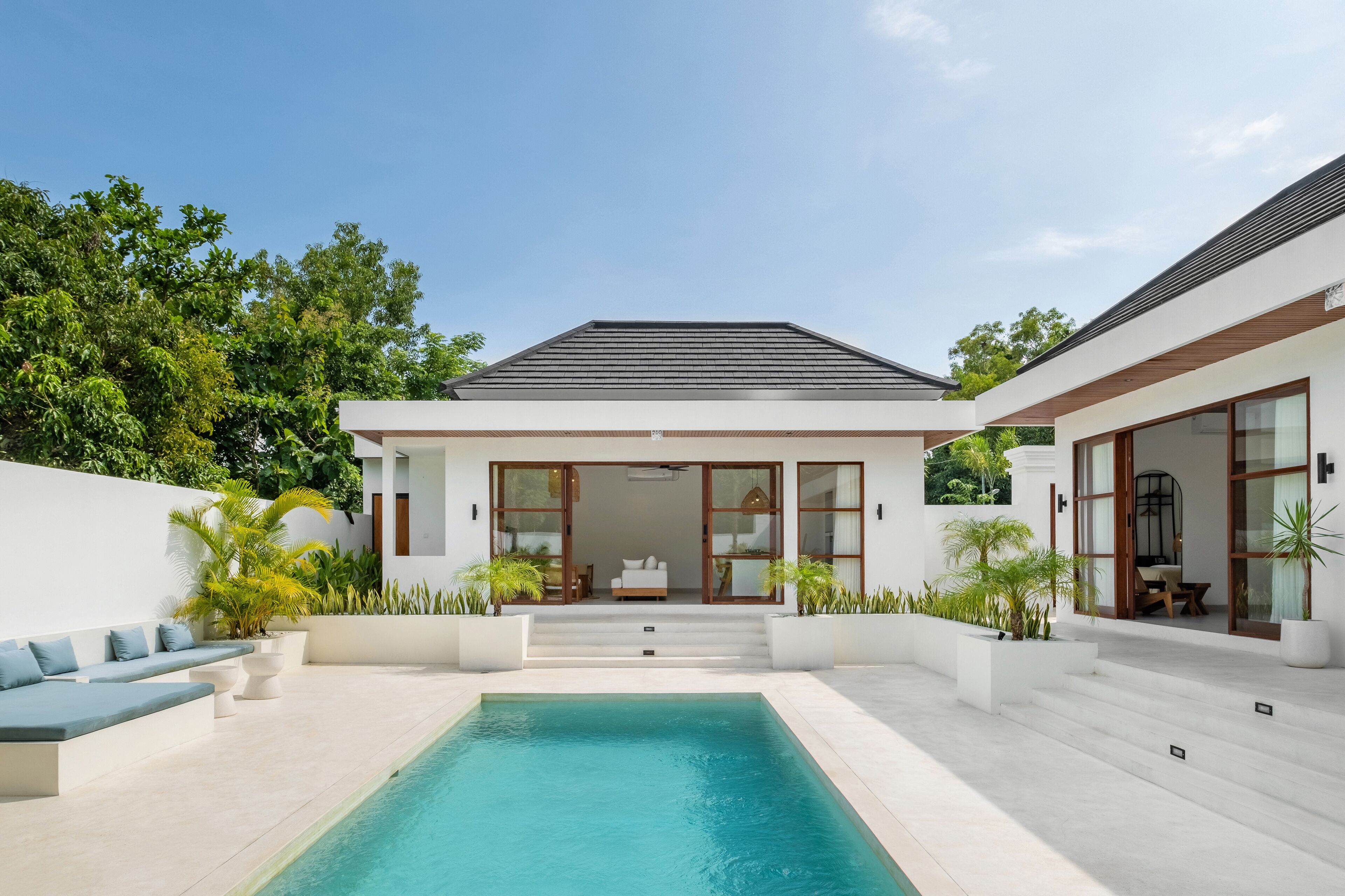 A modern house with a swimming pool, a patio with seating, and a view of the backyard.