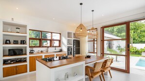 Une cuisine moderne avec des meubles en bois, un îlot central et un coin repas avec des chaises.