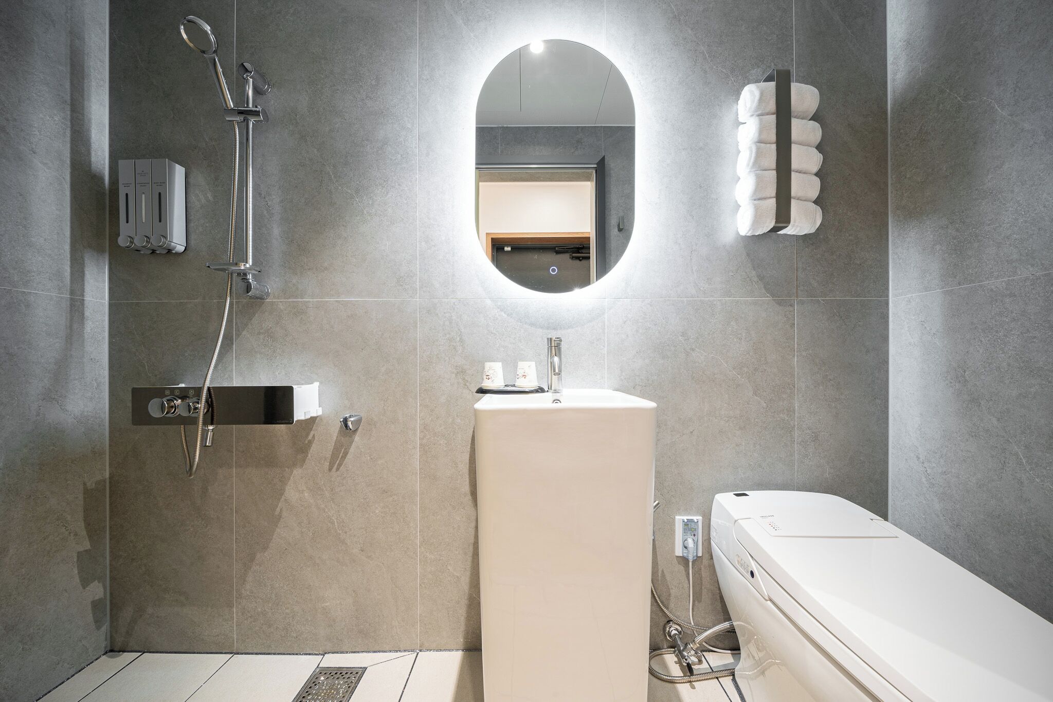 A modern bathroom with a shower, sink, and toilet.