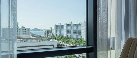 A view from a hotel room window overlooking a cityscape with high-rise buildings, a body of water, and a green park area.