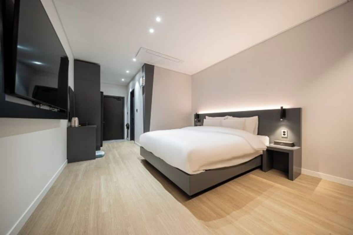 A modern bedroom with a bed, bedside table, and a wall-mounted TV.